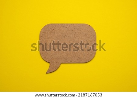 Brown wood speech bubble on yellow paper. Close up of paper blank speech bubble, isolated on yellow background with copy space for advertisement. Advertising area, mockup.