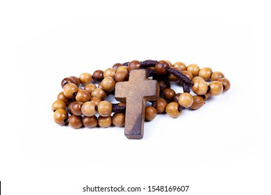 Brown Wooden Christian Rosary Curled Up, Christianity Religious Symbols Isolated On White. Cross Symbol In The Middle. Chaplet Of Divine Mercy Prayer Conept. Faith, Belief. Studio Shot