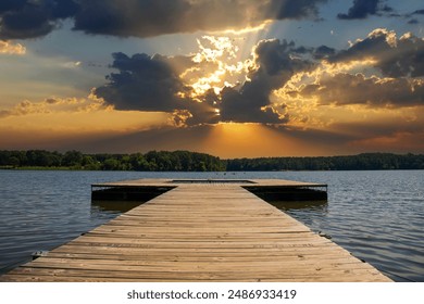 a brown wooden dock over the rippling blue waters of Lake Acworth surrounded by lush green trees and blue with powerful clouds at sunset at Cauble Park in Acworth Georgia USA - Powered by Shutterstock