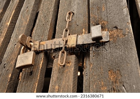 A brown, wooden door is securely closed and fastened with a padlock and bolt
