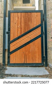 Brown Wooden Gate With Black Metal Frames At The Entrance Of A Building. Entrance To A Private Or Public Property With Shiny Brown Wood Slats Door At The Entryway.