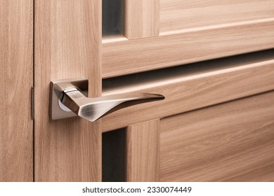 Brown wooden interior door with emphasis on metal handle. Close up of door handle on interior door with frosted glass inserts. Interior details or catalog for furniture store.