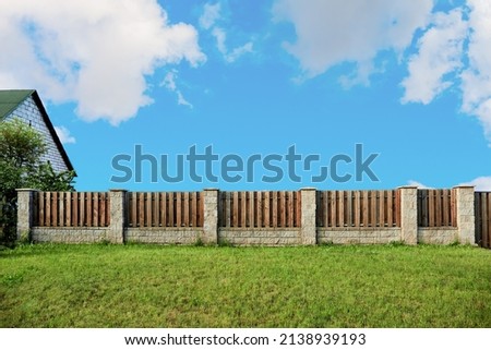 Brown wooden plank fence with block posts. House wall. Green grass lawn. Countryside private property. Minimalist landscape design. Rural real estate. Neighbors. Isolated mockup design. Exterior.