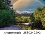 a brown wooden suspension bridge over a South Fork Peachtree Creek at Morningside Nature Preserve with lush green trees and plants in Atlanta Georgia USa