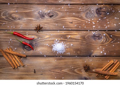 The brown wooden table is decorated with cinnamon, cloves, chili pepper and coarse table salt. Cooking concept. Copy space. - Powered by Shutterstock