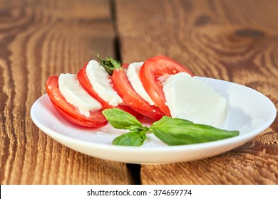 Brown Wooden Table With Tomato Mozzarella Basil Salad In Fresh Morning Light