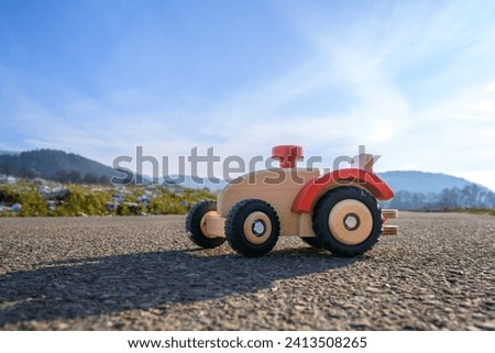 Brown wooden tractor with red steering wheel, toy tractor on a German asphalt road in winter in the sunshine