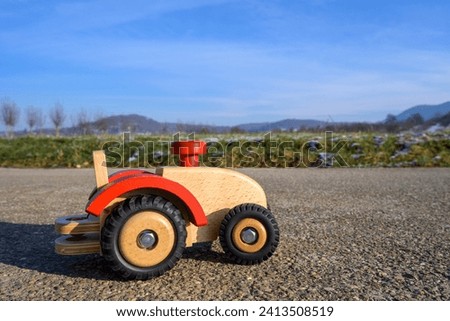 Brown wooden tractor with red steering wheel, toy tractor on a German asphalt road in winter in the sunshine