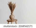 Brown wooden vase on a natural mango wooden stool with dried flowers in an empty room