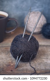 Brown yarn ball with knitting needles on a rustic wooden background, toned, wabi sabi style