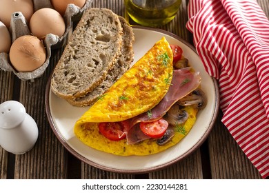 Browned omelette omelet stuffed with ham, mushrooms and cherry tomatoes - Shutterstock ID 2230144281