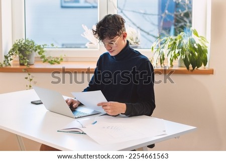 Brown-haired businessman transcribing his notes into his computer. A visionary puts his ideas into reality. Working from home. Online business.