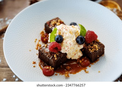 Brownie cake with salted caramel. Anglaise foam, raspberry sauce, praline nut and fresh berry. Delicious sweet dessert food closeup served for lunch in modern gourmet cuisine restaurant - Powered by Shutterstock