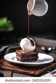 Brownie with vanilla ice cream, Chocolate sauce dripping on vanilla ice cream with brownie, placed on white plate