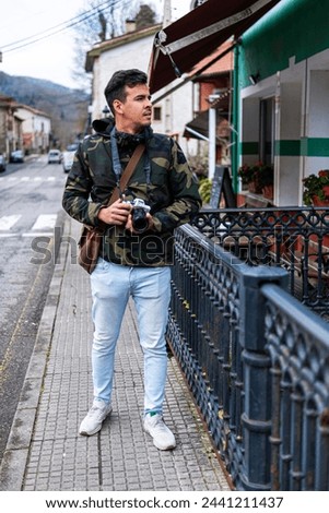 Brown-skinned Peruvian man in camo coat happily exploring Cabrales Asturias capturing moments camera
