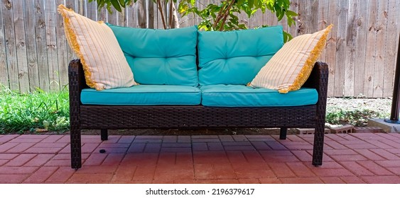 Brownsville TX USA July 10th 2022: An Outdoor Couch With Two Pillows Layed On It And A Wooden Fence In The Background Outside In The Backyard Patio.