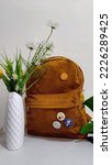 Browny bag with Corduroy material that is now hype among teenager. Blank bag usually is place for them to put pin or keychain as decoration. This bag standing beside beautiful flower vase