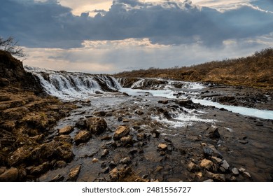 Bruarfoss Waterfall in Iceland with vibrant blue waters and a rugged landscape. - Powered by Shutterstock