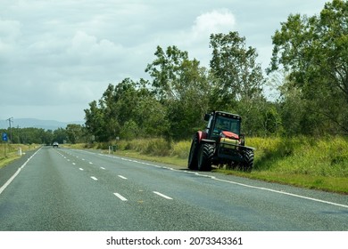 Bruce Highway Mackay To Townsville, Queensland, Australia - November 2021: Maintenance Worker Driving A Tractor To Mow The Grass On The Sides Of The Road