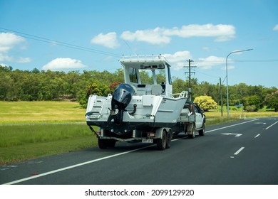 Bruce Highway, Proserpine, Queensland, Australia - December 2021: A Motor Boat On Trailer Towed By Small Truck Parked On Side Of A Country Road