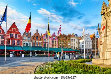 Bruges, Belgium. Central Market Square (Markt) in old town with medieval decorative houses and flags. Famous touristic landmark. Summer evening sunset time with blue sky.
