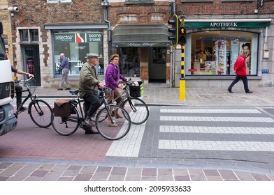 BRUGES, BELGIUM - CIRCA 2012 SEPTEMBER: An Older Male And A Female Cyclist Waiting At The Traffic Lights In A Shopping Area