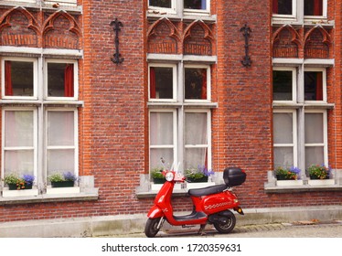 BRUGES, BELGIUM, EUROPE,JULY 1ST , 2017. A beautiful red vintage scooter parked outside a beautiful house in the streets of Bruges, BELGIUM