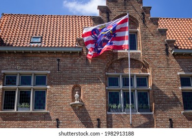 Bruges, Belgium; May 29th, 2021: Sculpture of the famous bear of Bruges in a red brick building with the flag of Bruges. Picture made from the tour in boat in the river. 