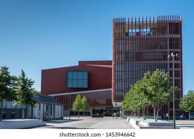 Bruges, Flanders, Belgium -  June 17, 2019: Contemporary Red Architecture Of The Concert Hall Or Concert Gebouw On The Zand Square Downtown. Blue Sky, People And Green Foliage.