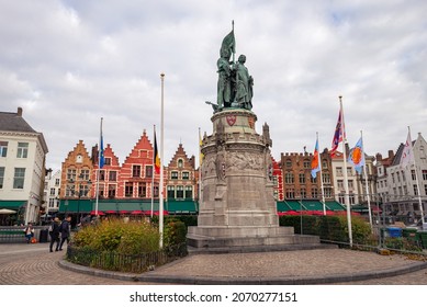 Brugge, Belgium - October 2021: Market square in the old town of Bruges. Statue of Jan Breydel and Pieter de Coninck, two of the heroes of the Golden Spurs and the beautiful facades of the market.
