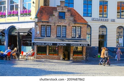 Brugge, Belgium - October 9. 2021: View over shopping street on old isolated lost medieval brick house chocolatier between modern buildings (focus on upper part of central house)