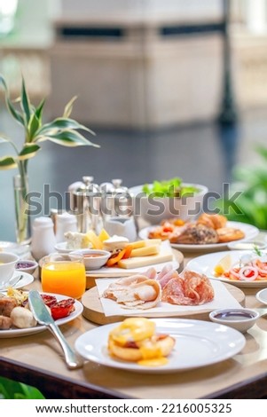 Brunch or lunch in luxury restaurant. Table full of delicious food - cheese, salmon, ham, bakery and juices. Buffet food in hotel. Morning food with various snacks and appetizers.