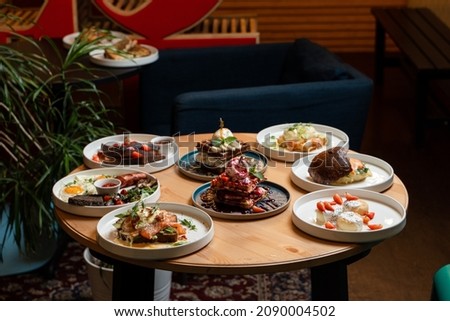 Brunch meals on wooden table, side view of served round table