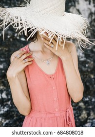Brunette in accessories hiding face under big straw hat. 
