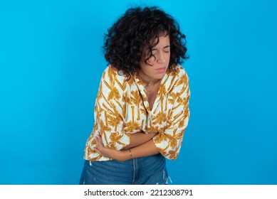 Brunette Arab Woman Wearing Hawaiian Shirt Over Blue Background Got Stomachache