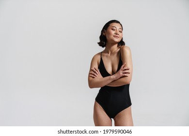 Brunette asian woman wearing swimsuit posing with arms crossed isolated over white background