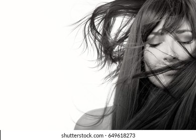 Brunette Beauty Model Girl With Healthy Straight Long Hair Blowing Over Her Face Wearing Subtle Eye Makeup In A Monochrome Closeup Beauty Portrait With Copy Space. Haircare Concept