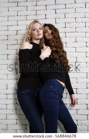 brunette and the blonde on the background of brick wall