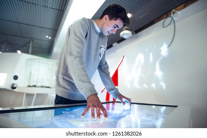 Brunette Boy Interacting With Large Touch Screen In Museum Stand Exhibition