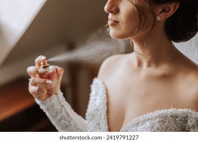 The brunette bride, holds perfume in her hands, wants to apply it on herself. Voluminous veil. Beautiful hands. Open bust - Powered by Shutterstock