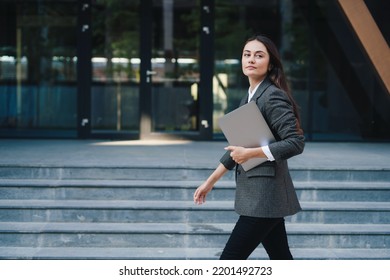 A brunette businesswoman walking in city street with laptop going to work in the morning. Copy space. Getting outside for a change. Businessman holding laptop