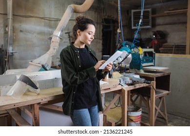 Brunette carpenter using digital tablet near protective visor and equipment in workshop