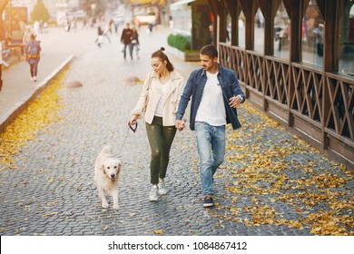 Brunette Couple Walking Their Golden Retriever Dog In The City On A Sunny Autumn Day