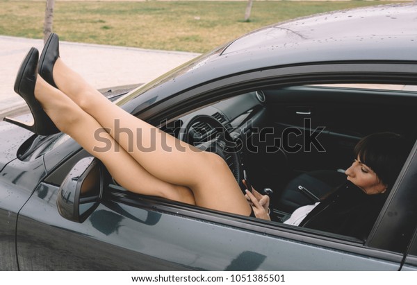 Brunette\
executive woman in car window peeks\
legs.