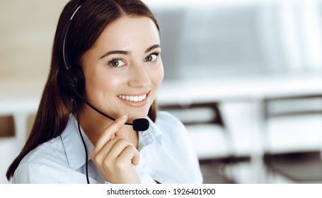 Brunette female customer service representative in a headset is consulting clients online. Call center and business people concept