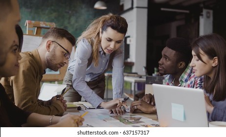 Brunette female team leader talking with mixed race group of people, writes with a marker on the model of house. - Shutterstock ID 637157317