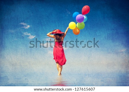 Brunette girl with colour balloons at coast. Photo in old color image style.