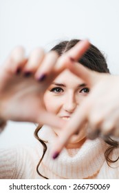 brunette girl doing camera hands and fingers on a white background
