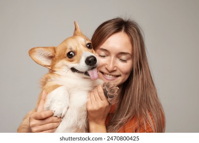 a brunette girl holds and hugs a red corgi dog on a clean light background, the concept of love for animals - Powered by Shutterstock