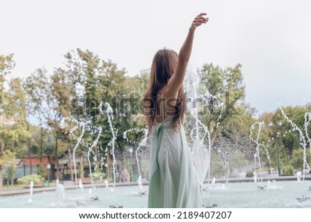 Brunette girl in light blue dress near the fountain with dried flowers